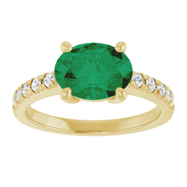 Side view of a 14K yellow gold oval emerald ring showing its four-prong center setting and diamond-accented shoulders
