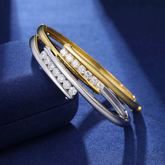 Two gold and silver bracelets with diamond accents on a blue background