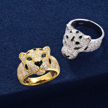 Two leopard-shaped rings, one gold and one silver, on a dark blue background.