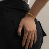 Hand wearing a gold bracelet on a black background