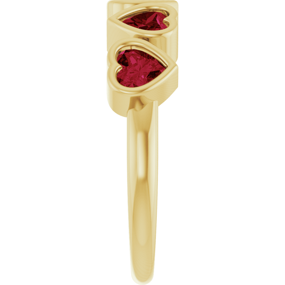 Side profile of a solid 14K yellow gold ring showing its raised heart-shaped garnet bezel settings