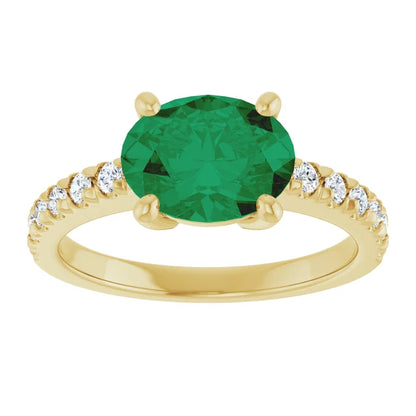 Side view of a 14K yellow gold oval emerald ring showing its four-prong center setting and diamond-accented shoulders