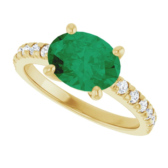 Side view of a 14K yellow gold oval emerald ring showing its four-prong center setting and diamond-accented shoulders