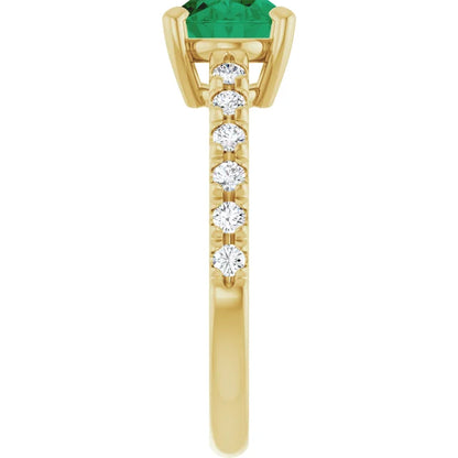 Side view of a 14K yellow gold oval emerald ring showing its four-prong center setting and diamond-accented shoulders