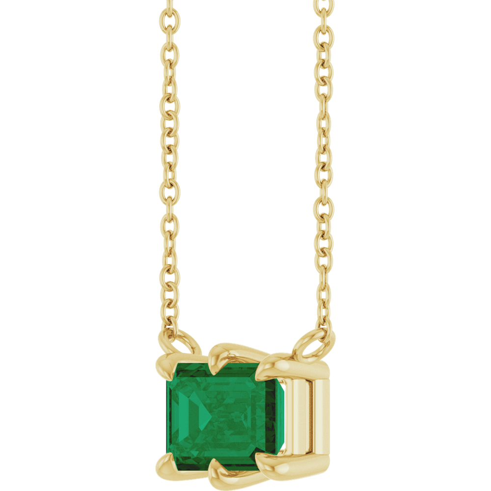 Detailed view of the polished 14K yellow gold six-prong setting on a lab-grown emerald solitaire necklace
