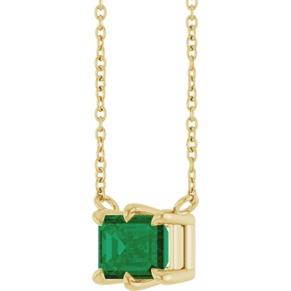 Detailed view of the polished 14K yellow gold six-prong setting on a lab-grown emerald solitaire necklace
