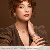 Woman wearing gold jewelry including a bracelet, necklace, and rings on a brown background