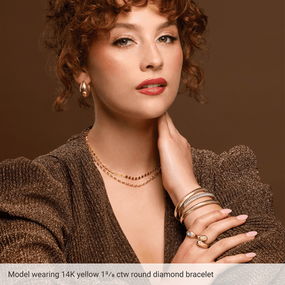 Woman wearing gold jewelry including a bracelet, necklace, and rings on a brown background