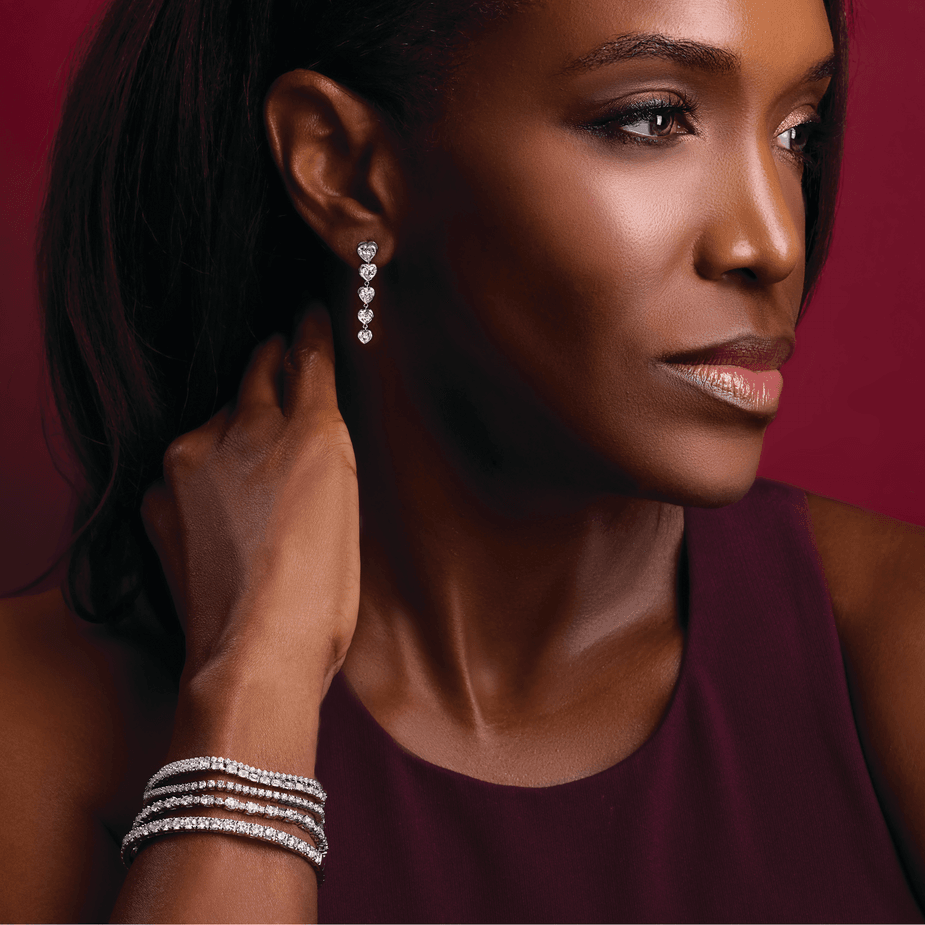 Woman wearing diamond earrings and bracelet against a red background