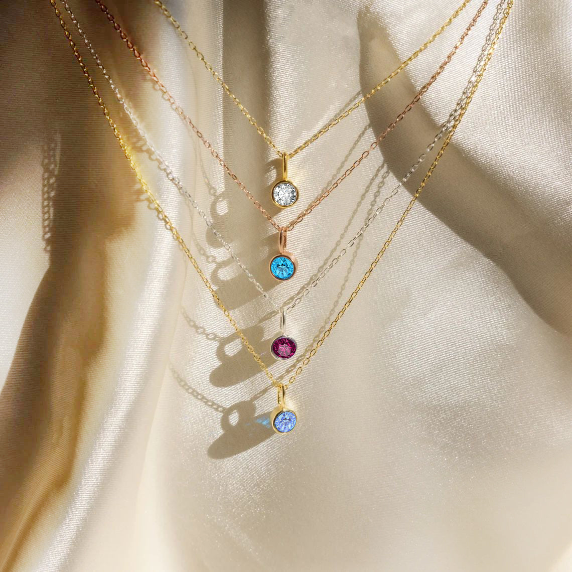 Gold necklaces with colorful gemstones on a beige fabric background