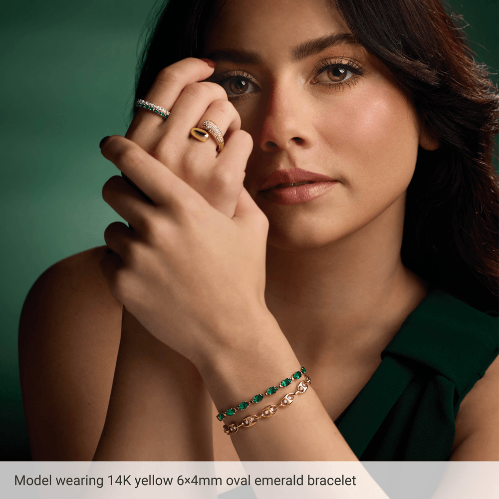 Model wearing Guerilla Choice 14K yellow gold oval emerald bracelet in luxury editorial styling