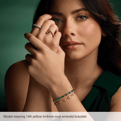 Model wearing Guerilla Choice 14K yellow gold oval emerald bracelet in luxury editorial styling