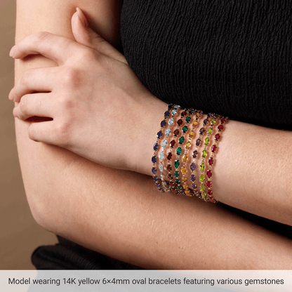Model wearing stacked Guerilla Choice 14K yellow gold gemstone bracelets in luxury editorial styling