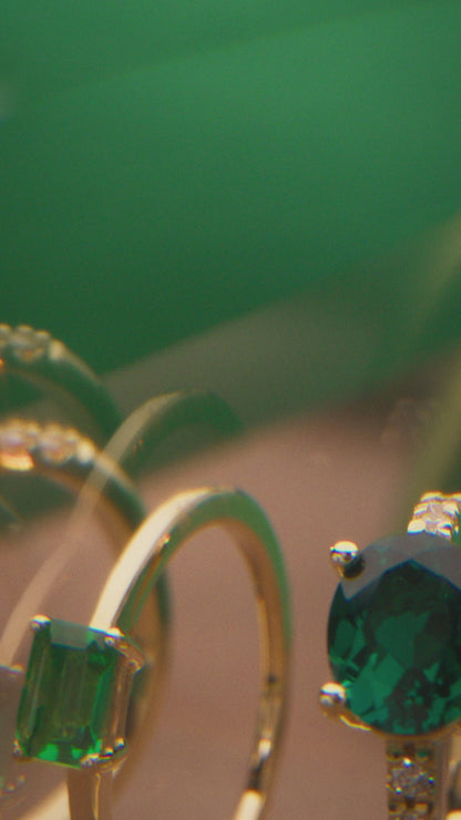 Side view of a 14K yellow gold oval emerald ring showing its four-prong center setting and diamond-accented shoulders