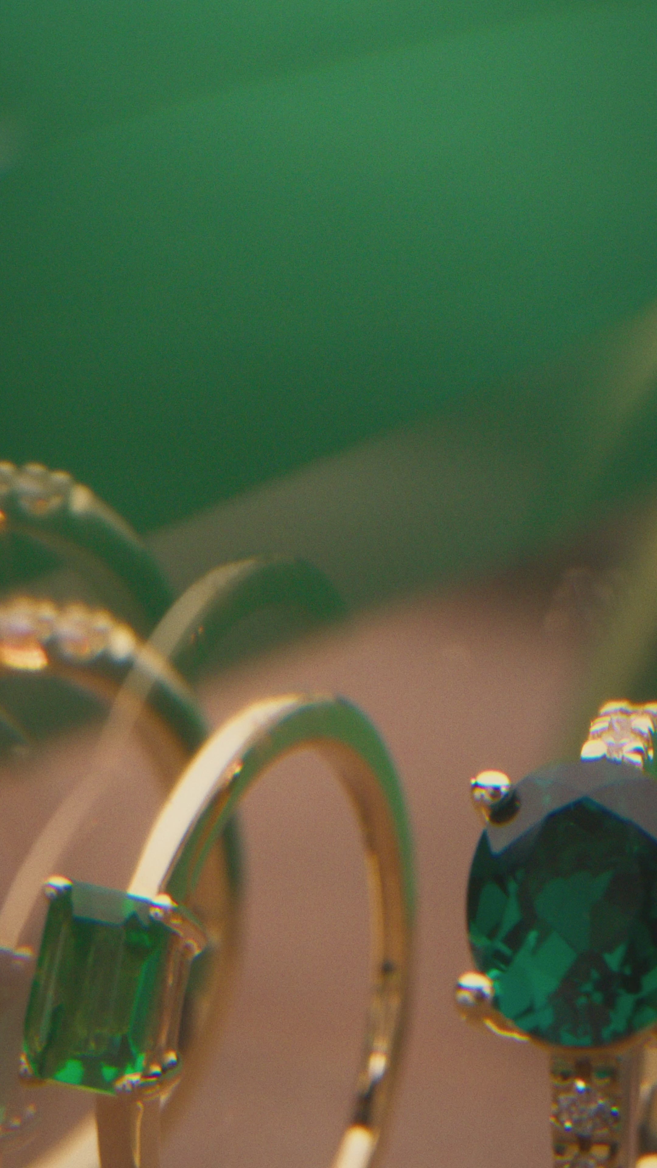 Side view of a 14K yellow gold oval emerald ring showing its four-prong center setting and diamond-accented shoulders